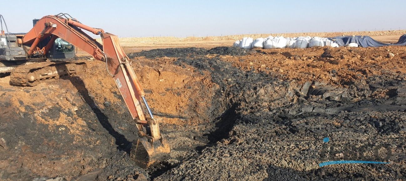 بیل مکانیکی در حال خاک‌برداری پسماند نفتی از گودال.